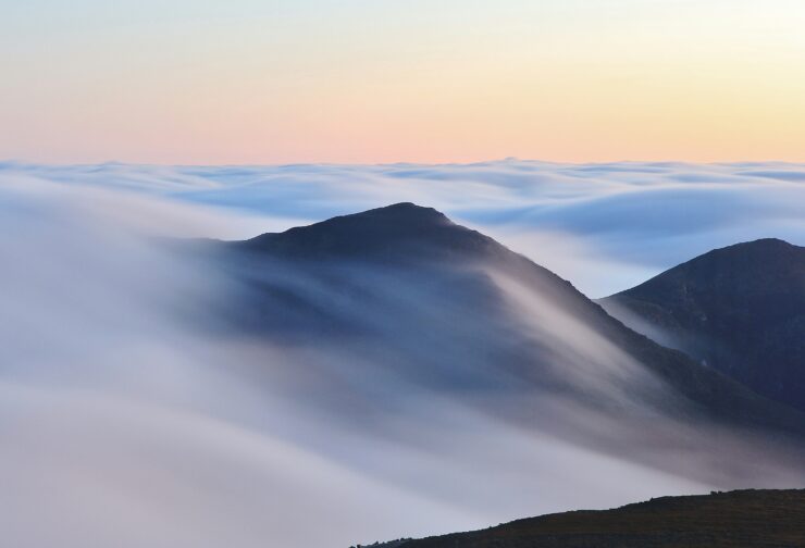 A visible summit above dense fog, where what can be seen suggests certainty, but the underlying terrain remains hidden.
